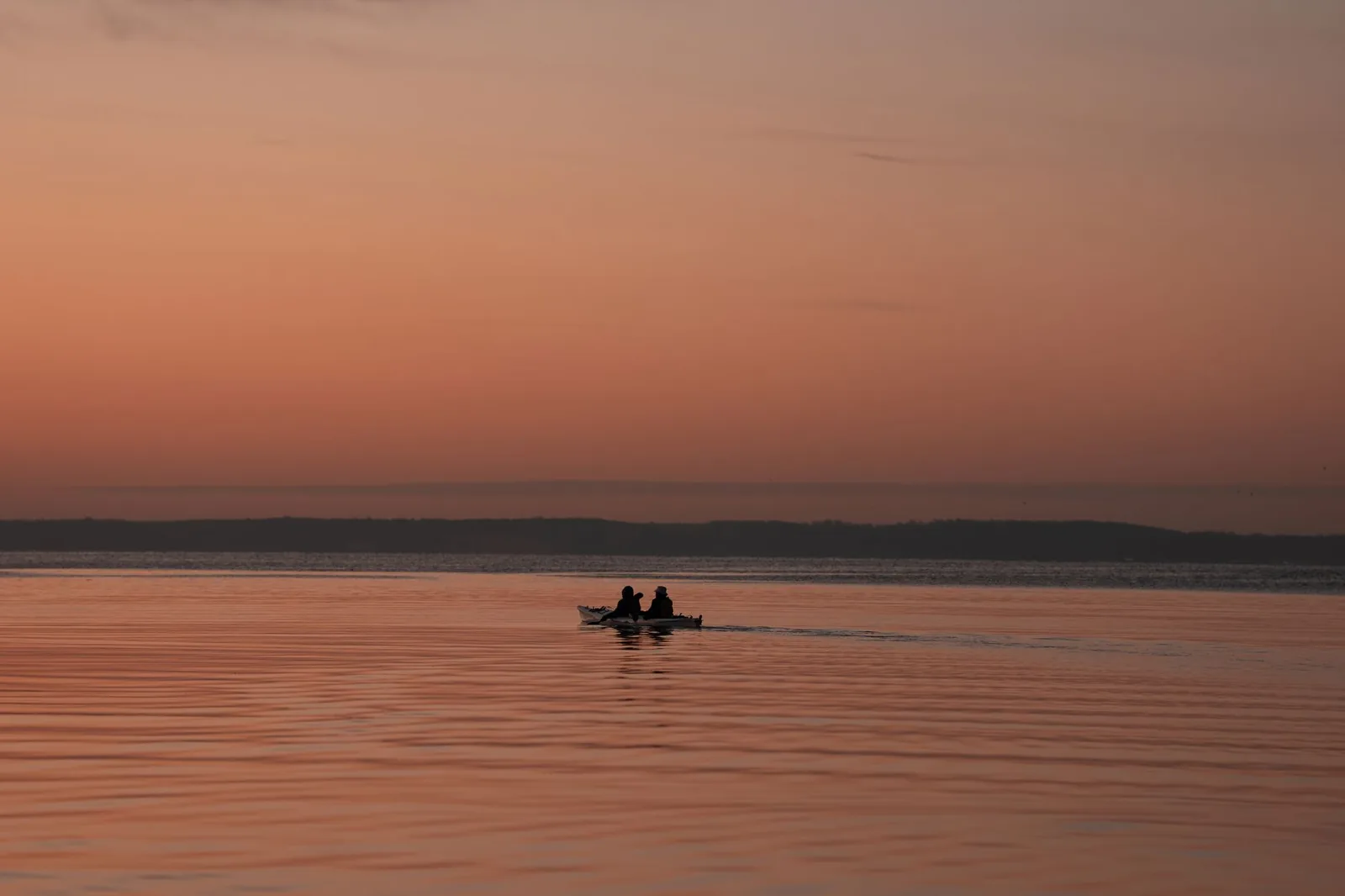 A canoe gliding across still water on the Toccoa River at sunrise, mist rising off the surface
